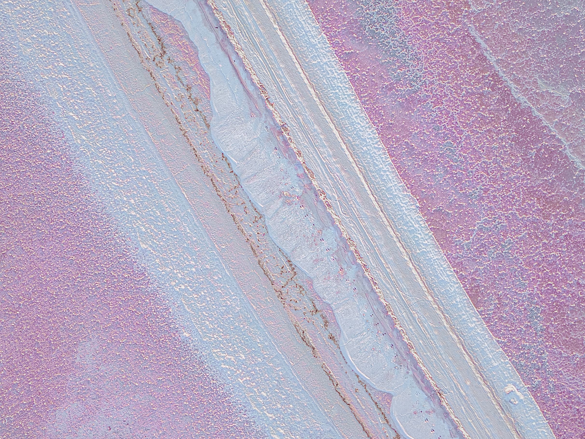 Diagonal bands of pink and blue sediment cutting across a salt flat
